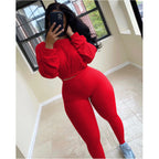 Woman wearing a vibrant red, ribbed two-piece leisure set with a long-sleeve crop top and matching high-waist leggings.