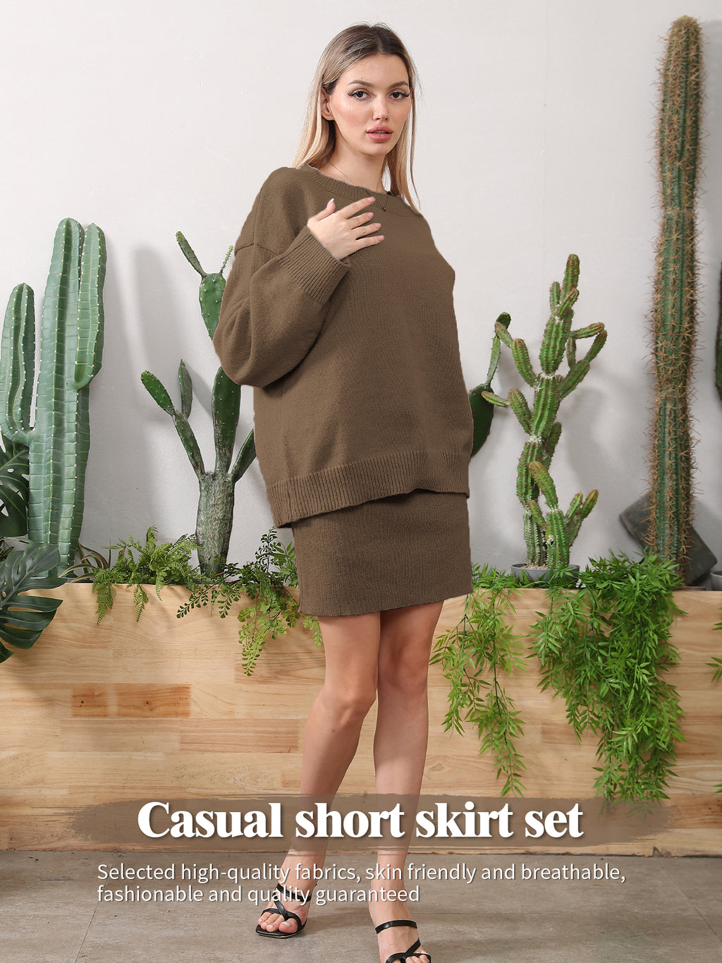 A woman wearing a brown knit sweater and matching short skirt, standing in front of cacti and greenery.