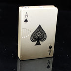 Gold metal playing card-style lighter, Ace of Spades design with detailed black engraving, standing on black surface.