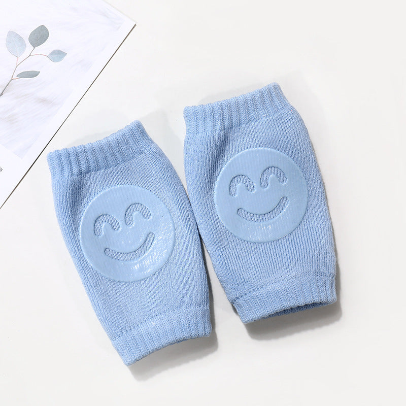 Pair of light blue baby terry knee pads featuring a rubberized smiling face design for crawling protection.