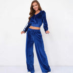 A woman models a royal blue velour tracksuit with a cropped zip-up hoodie and matching wide-leg drawstring pants.