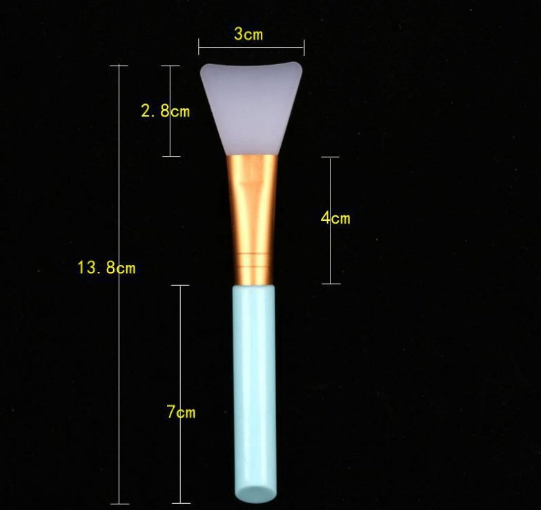 Silicone face mask brush with a white flexible head, gold ferrule, and light blue handle, featuring size annotations.