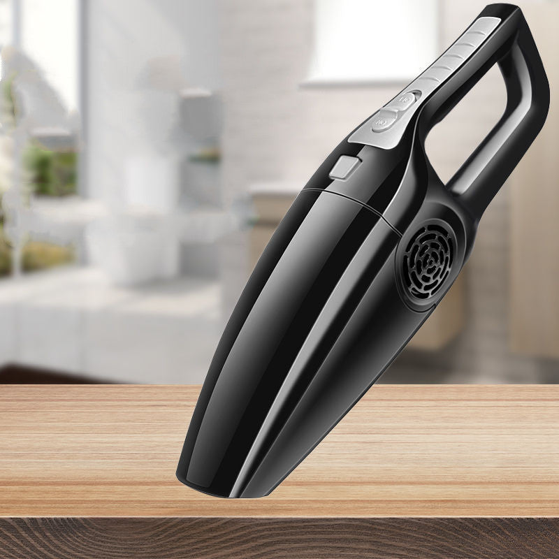 Sleek, black wireless handheld car vacuum with silver control buttons on a wooden surface against a blurred background.