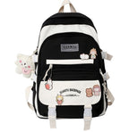 Black and white Korean-style backpack featuring cute character patches, hanging plush charm, and dual buckle straps.