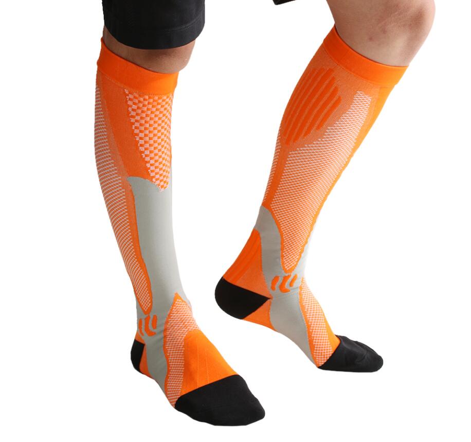 Person wearing orange, grey, and black athletic compression socks with knit textures, isolated on white background.