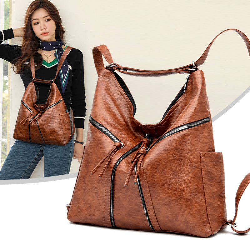 Brown soft leather convertible backpack/shoulder bag with diagonal zippered pockets, tassels, and adjustable straps.