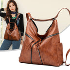 Brown soft leather convertible backpack/shoulder bag with diagonal zippered pockets, tassels, and adjustable straps.