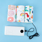 Three patterned fabric USB bottle warmers connected to a white portable power bank on a light blue background.