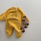 Yellow long-sleeve baby jumpsuit with a teddy bear graphic and "How about you?" text, paired with brown bear socks.