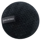 A circular, black textured makeup sponge by Digitaldistribution375 featuring a "CLEAN SPONGE" label on a white background.