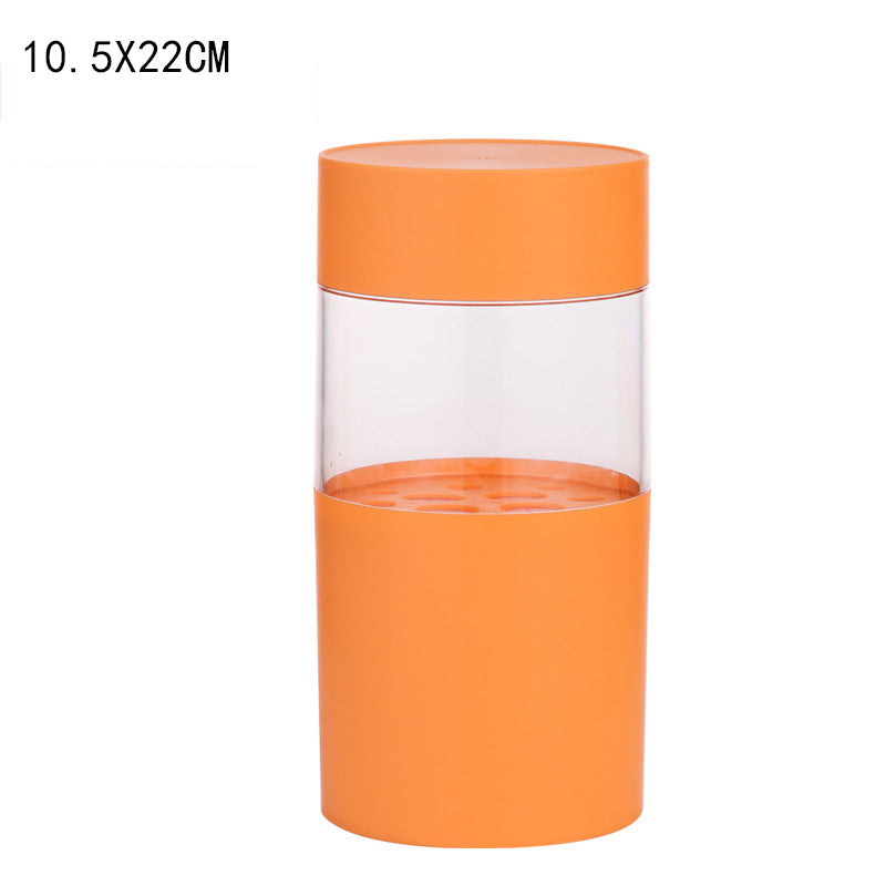 Orange cylindrical makeup brush holder with a clear middle section and internal organizer base for brushes and pencils.