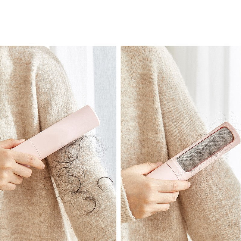 A hand using a light pink, handheld pet hair remover brush with a textured metal cleaning surface on a beige sweater.