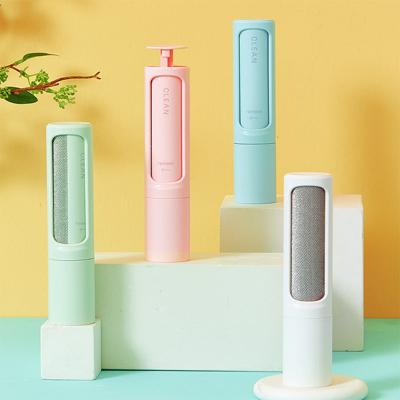 Four colorful, portable pet hair removal brushes with fabric inserts stand on white blocks against a yellow background.