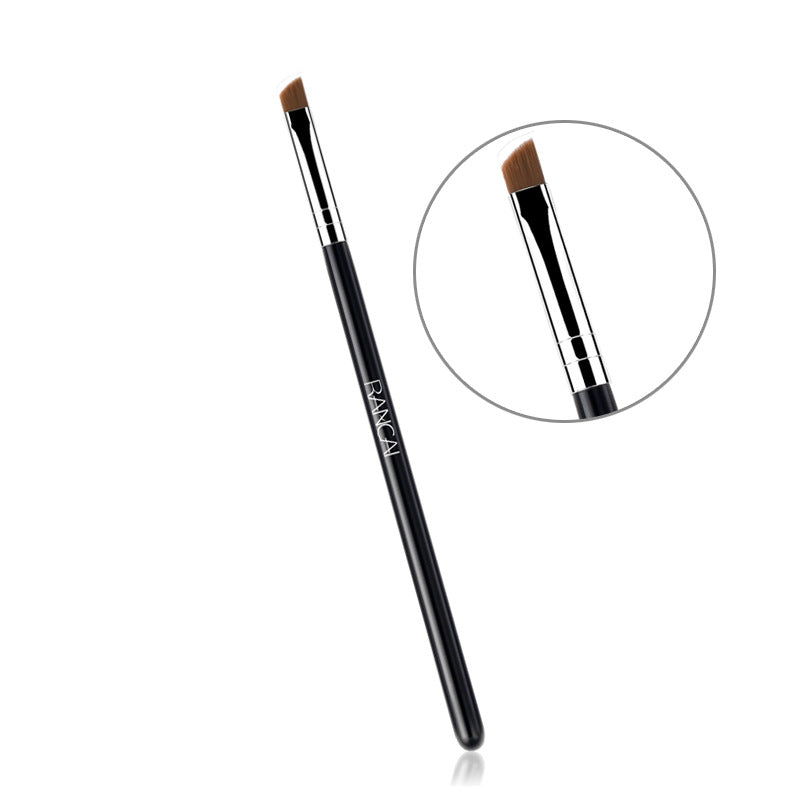 Black slanted eyebrow brush with a silver ferrule and brown bristles, featuring a close-up detail circle.