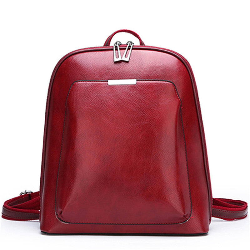 Red leather-like women's backpack with dual zippers, a front pocket, and adjustable straps on a white background.