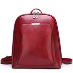Red leather-like women's backpack with dual zippers, a front pocket, and adjustable straps on a white background.