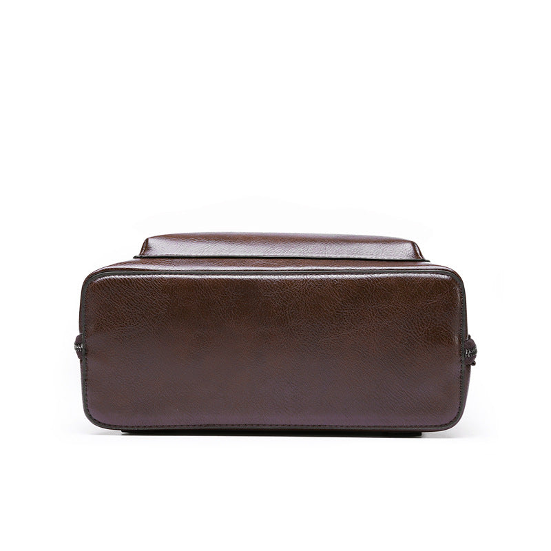Bottom view of a rectangular, dark brown, textured leather-look structured bag with side zippers on a white background.