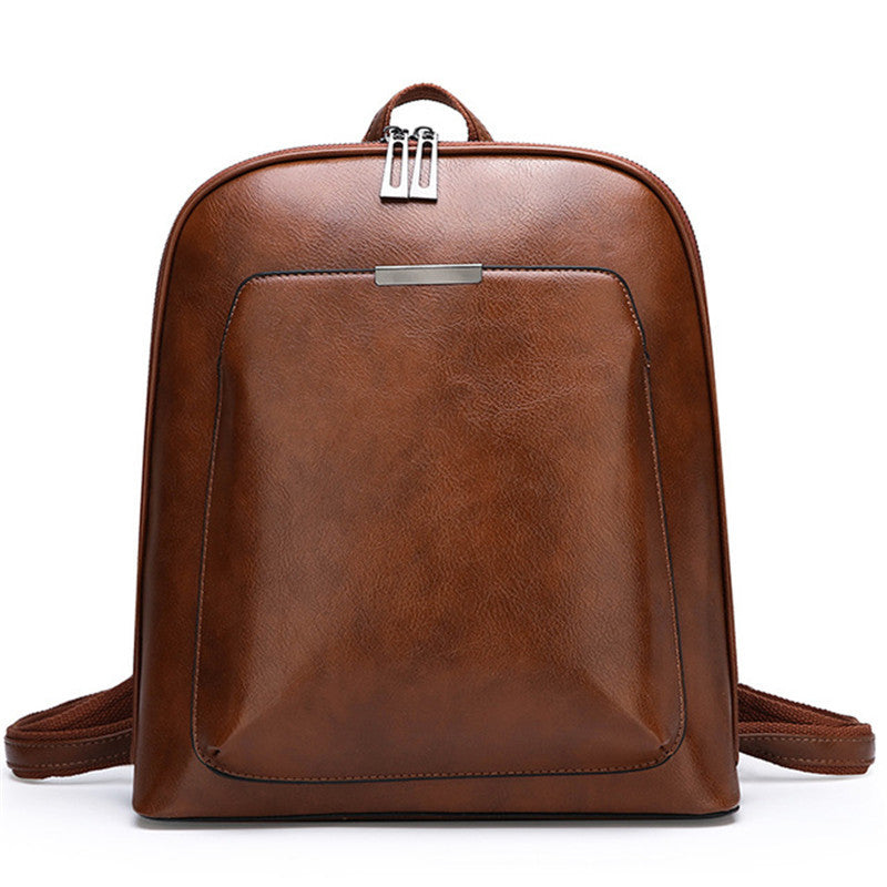 Brown leather backpack with a clean, minimalist design, front zipper pocket, silver hardware, and adjustable straps.