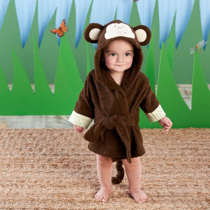Toddler wearing a brown, cotton monkey-themed hooded bathrobe with a tie waist, standing on a textured mat.