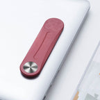 A red, slim aluminum side-screen phone mount attached to a silver laptop lid.
