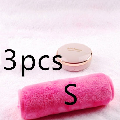 A soft, pink plush makeup remover towel resting on a white fuzzy surface next to a blush-colored compact.