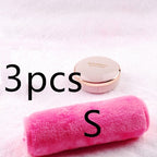 A soft, pink plush makeup remover towel resting on a white fuzzy surface next to a blush-colored compact.