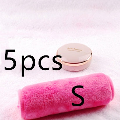 A bright pink plush makeup remover towel resting on a soft white fabric surface next to a small, round compact case.