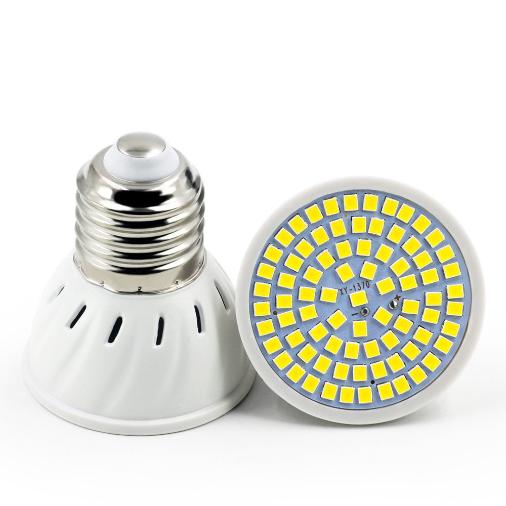 A white plastic energy-saving LED lamp cup with a metallic screw base and a circular array of yellow LED chips.