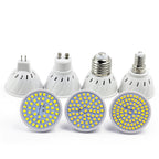 Four white plastic energy-saving LED lamps with circular heads featuring yellow diode arrays and various base types.