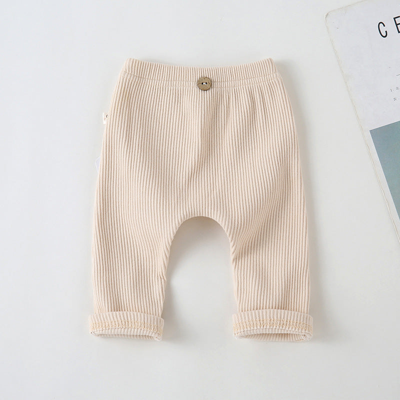 Beige ribbed baby leggings with an elastic waistband and decorative wooden button, featuring cuffed ankles.