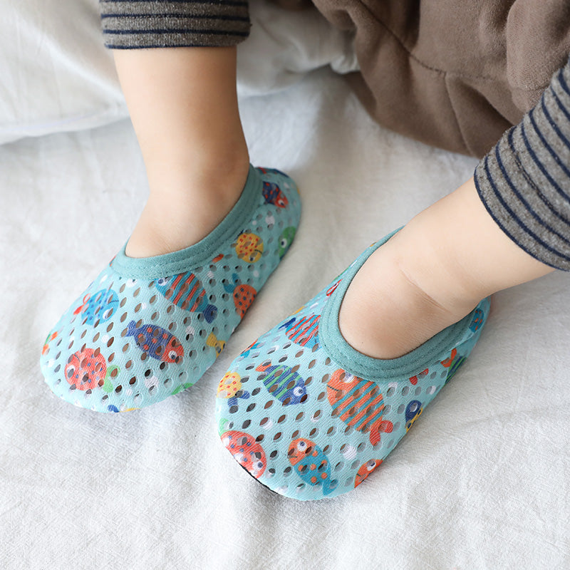 Light blue baby mesh shoes with colorful fish patterns and solid trim, worn on a baby's feet.