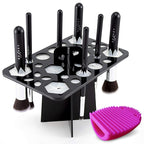 Black 14-hole acrylic makeup brush drying rack with silicone inserts, plus a pink silicone brush cleaning mat.