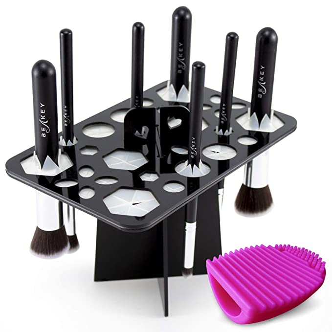 Black 14-hole acrylic makeup brush drying rack with silicone inserts, plus a pink silicone brush cleaning mat.