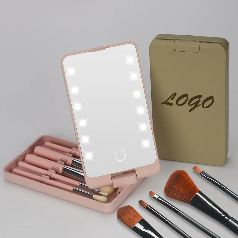 Pink folding LED makeup mirror with a set of makeup brushes inside and a closed tan case on the side.