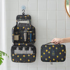 Black travel toiletry bag with yellow lemon print, hanging hook, clear pockets, and organized mesh compartments.
