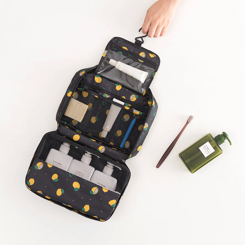 Black travel toiletry bag with lemon print, hanging hook, and mesh compartments, filled with personal care items.