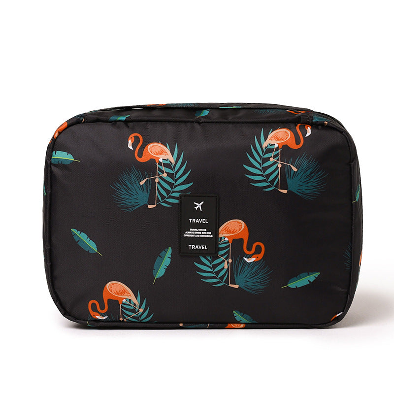 Black travel cosmetic bag with orange flamingo and teal leaf pattern. Features a centered "TRAVEL" logo patch.