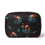 Black travel cosmetic bag with orange flamingo and teal leaf pattern. Features a centered "TRAVEL" logo patch.