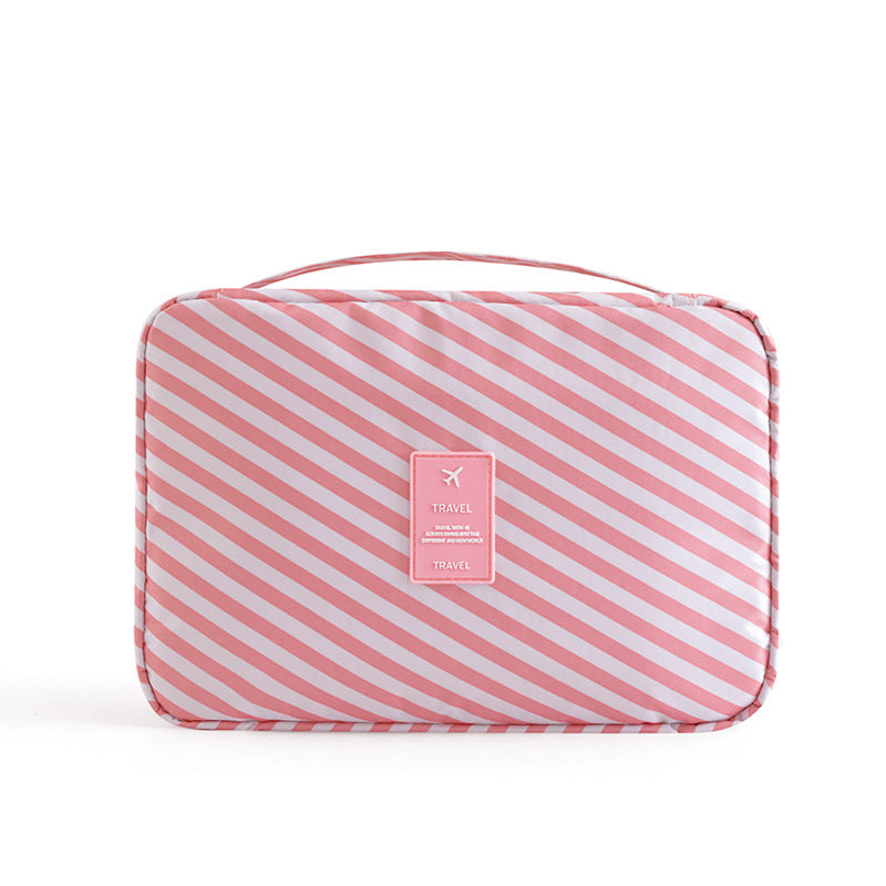 Pink and white striped travel cosmetic bag with top handle and centered "TRAVEL" logo patch on white background.