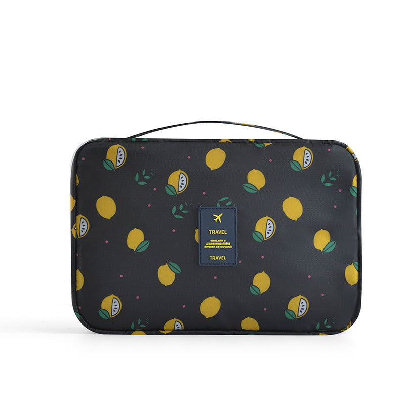 Black travel cosmetic bag with yellow lemon print, top handle, and a central blue "TRAVEL" tag.