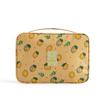Yellow travel makeup bag featuring a lemon print, carrying handle, and a central "TRAVEL" logo patch on a white back.