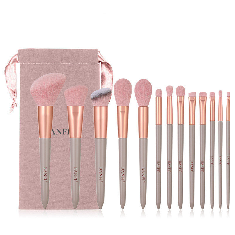13-piece Banfi makeup brush set with soft pink bristles, rose gold ferrules, grey handles, and a pink velvet pouch.