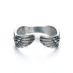 Silver-tone metal open-style ring featuring detailed engraved angel wings on each side. Isolated on white background.
