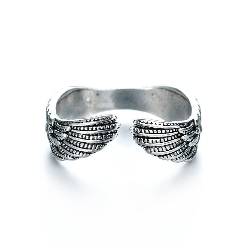 Silver-tone metal open-style ring featuring detailed engraved angel wings on each side. Isolated on white background.