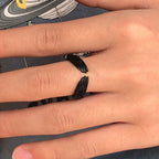 Matte black, open-style ring featuring detailed textured angel wings wrapped around a finger.