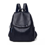 Navy blue soft leather women's backpack with a front flap, top handle, and adjustable shoulder straps.