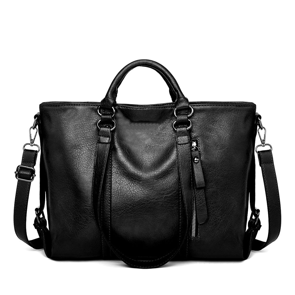 Black soft leather large tote bag with top handles, zippered front pocket, and adjustable shoulder strap.