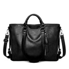 Black soft leather large tote bag with top handles, zippered front pocket, and adjustable shoulder strap.