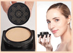 Black air cushion compact with beige BB cream and a mushroom-shaped applicator sponge; woman holding the product.