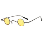 Retro-style glasses with small, round, yellow-tinted lenses and a slim, dark grey metal frame on a white background.